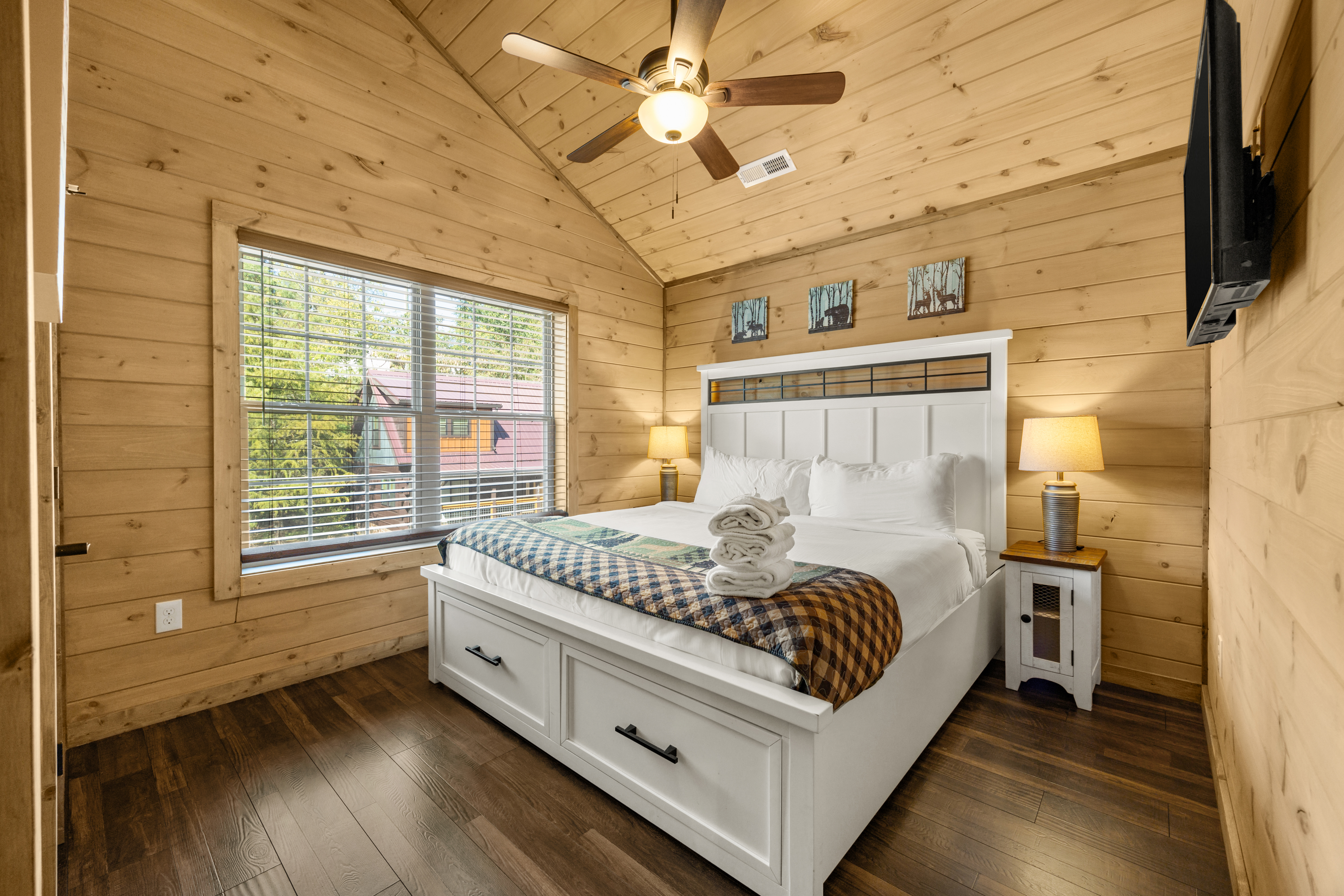 Cozy wood-paneled bedroom with vaulted ceiling, TV, and natural light