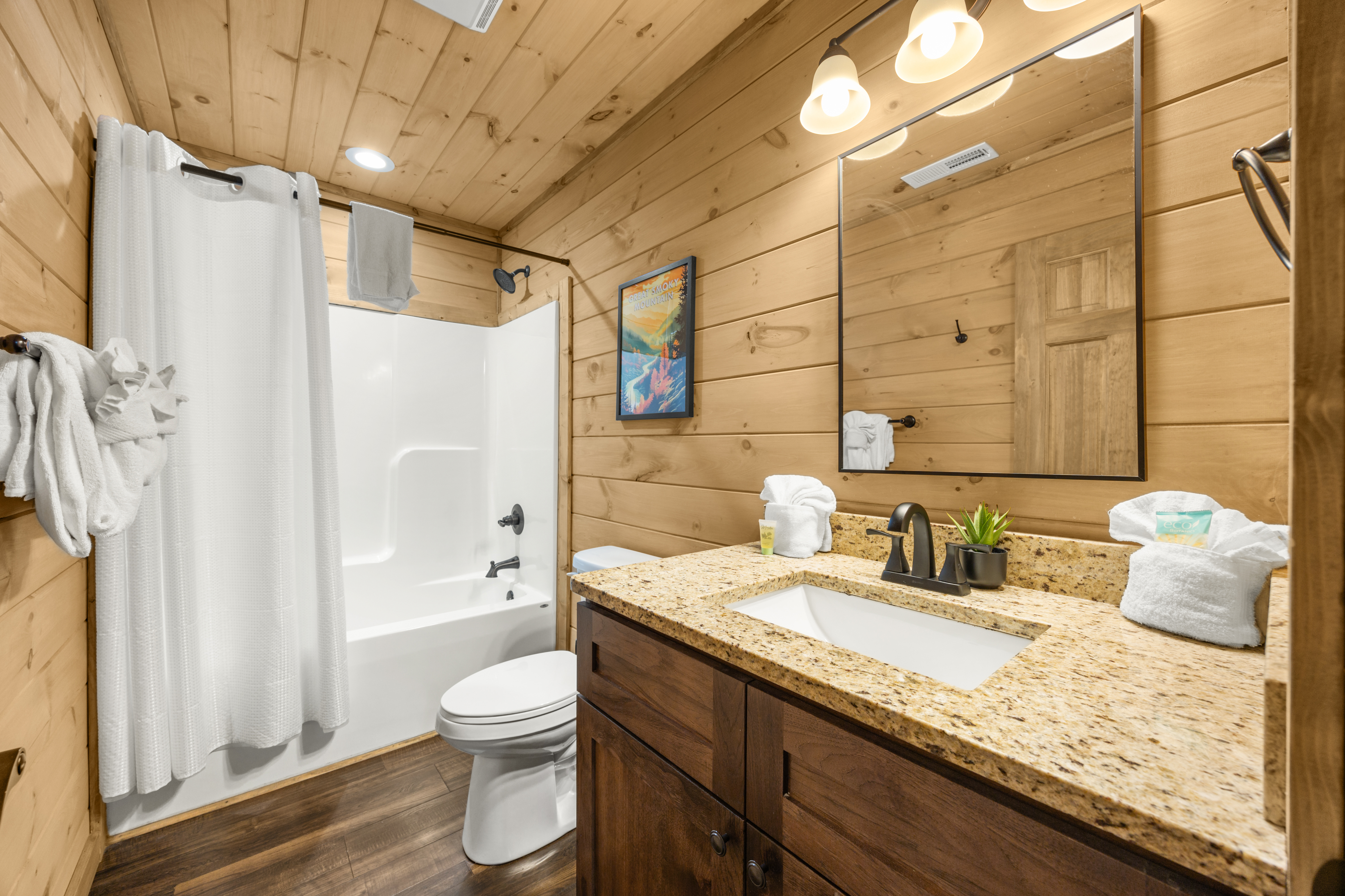 Cozy cabin-style bathroom with granite vanity and tub-shower combo