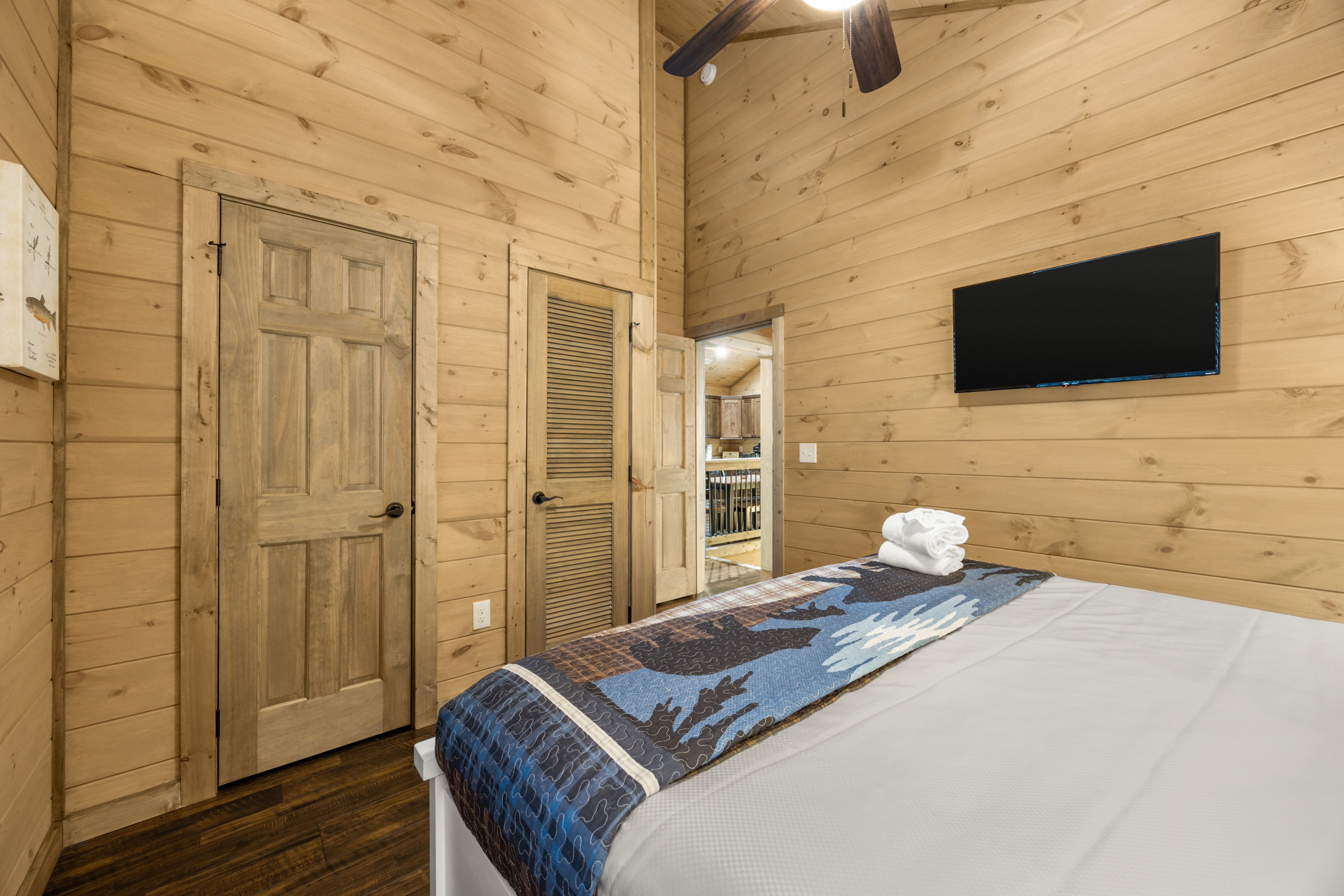Cozy wood-paneled bedroom with vaulted ceilings and in-room TV