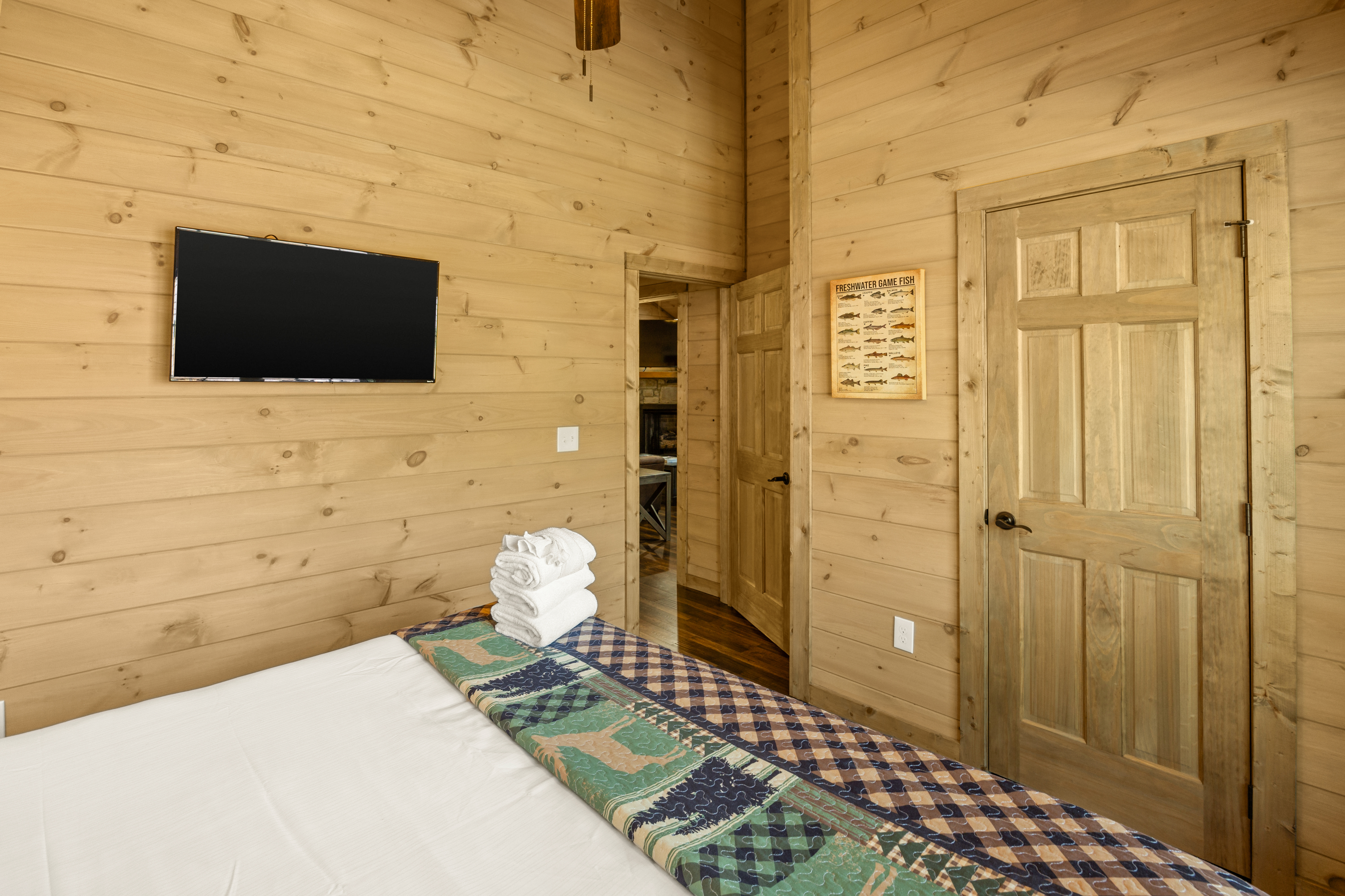 Cozy wood-paneled bedroom with TV and warm rustic cabin charm