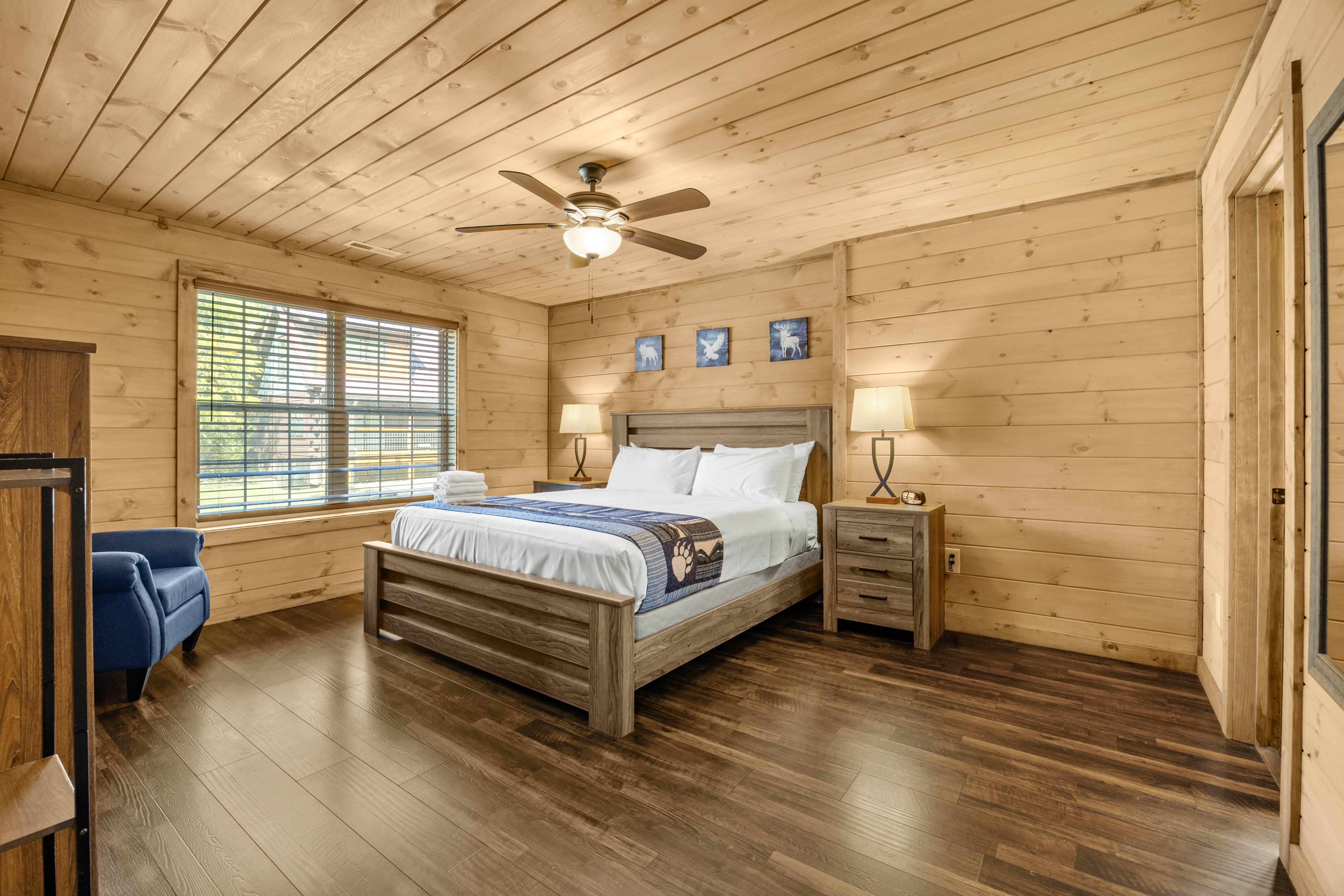 Cozy wood-paneled king bedroom with natural light and cabin charm