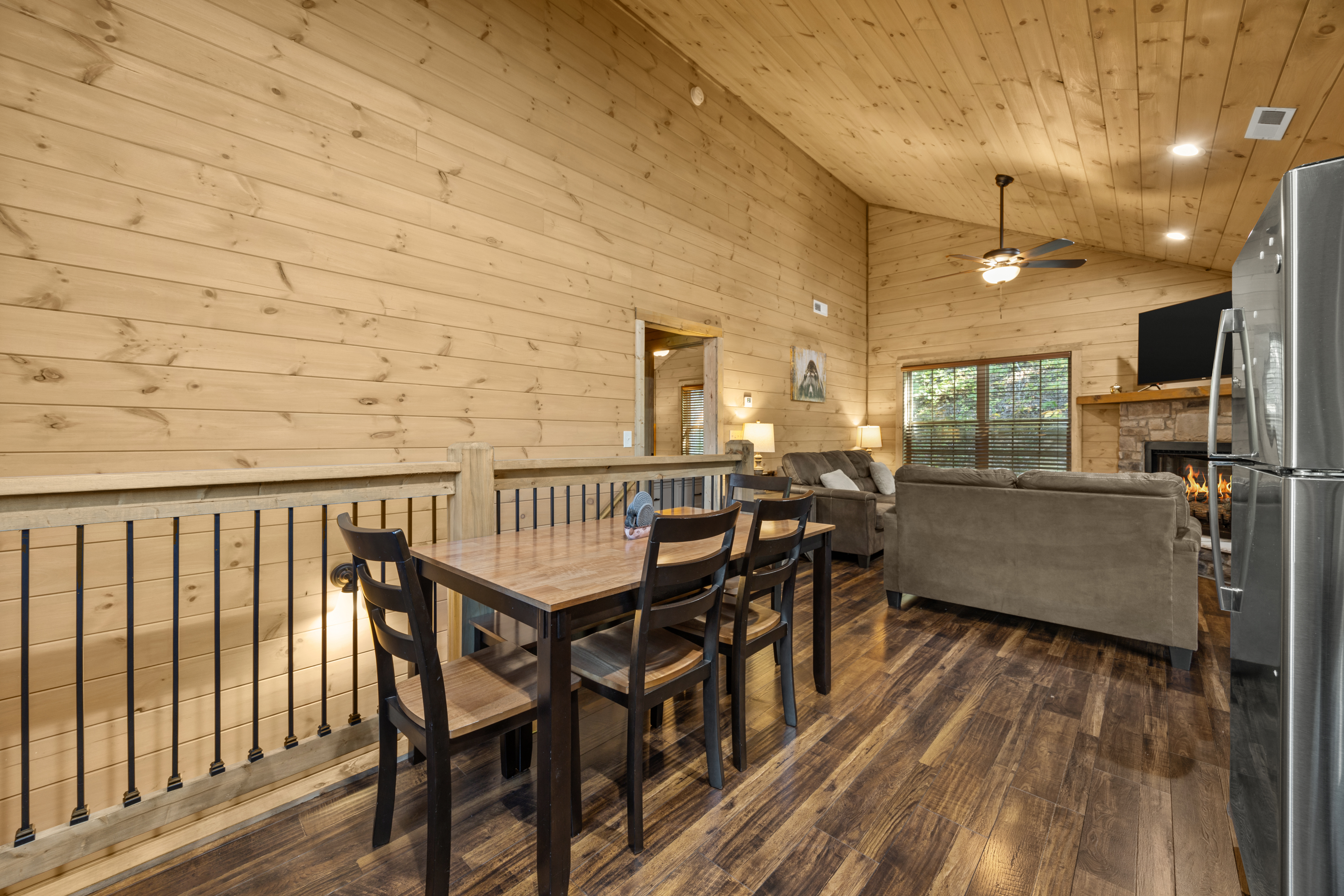 Cozy loft-style great room with fireplace, dining space, and warm wood charm
