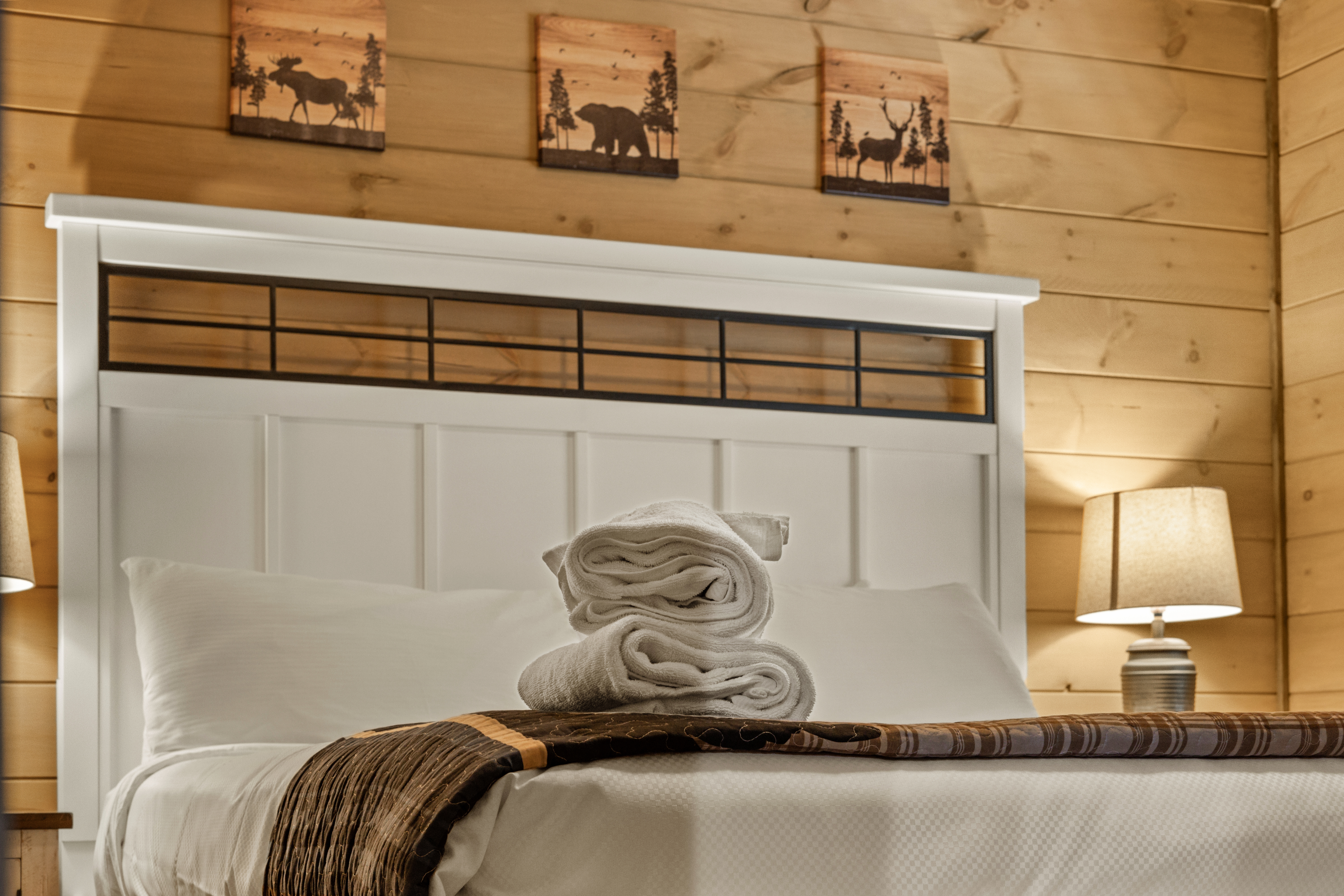 Cozy cabin-style bedroom with warm wood walls and plush guest-ready bed