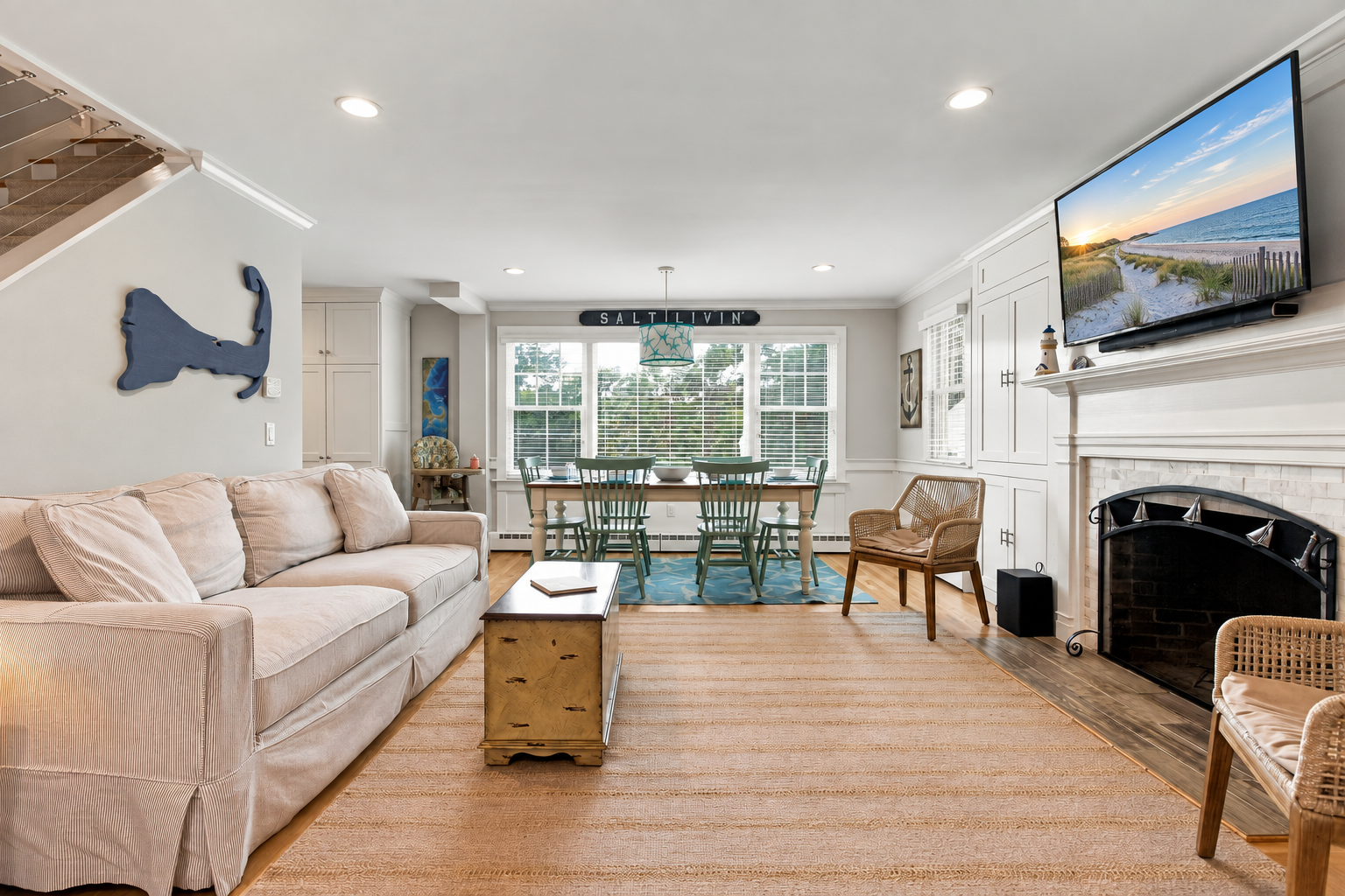 Bright coastal living room with fireplace, TV, and sunny dining nook