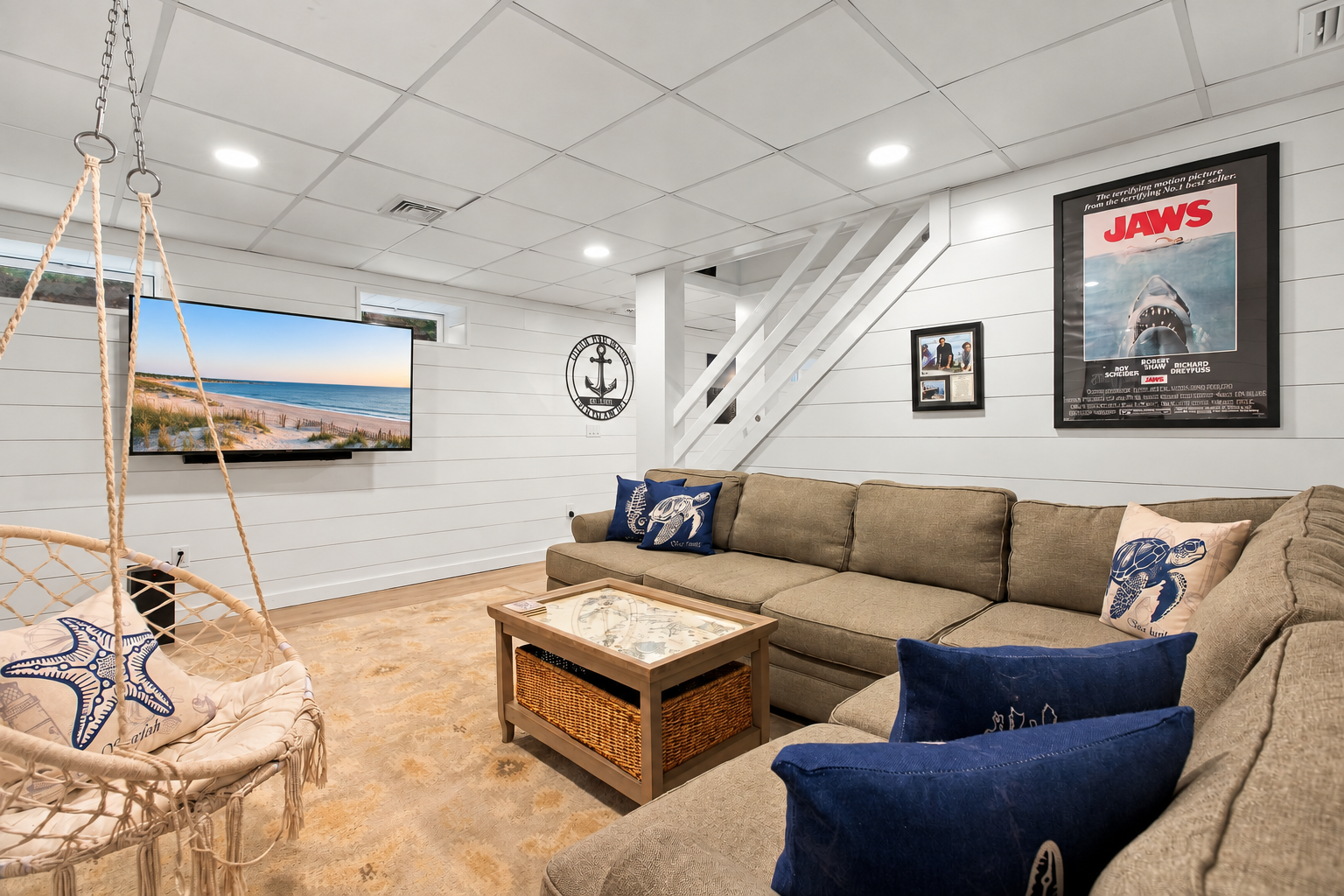 Cozy coastal lounge with big sectional, TV, and fun hanging chair