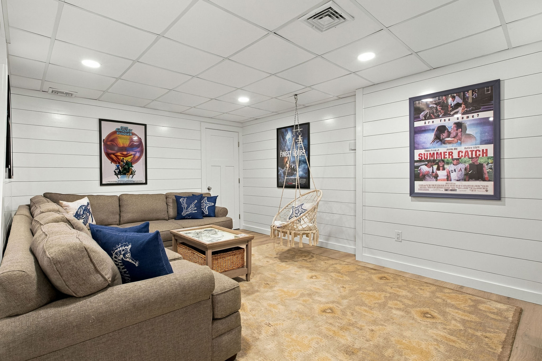 Cozy lounge with large sectional, movie posters, and fun hanging chair