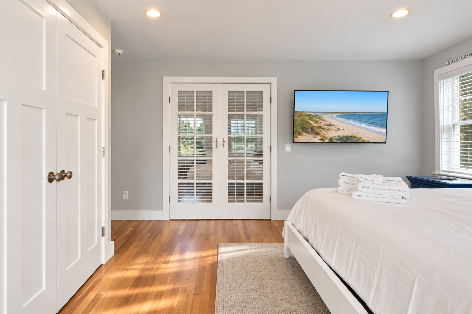 Bright coastal bedroom with hardwood floors and elegant French doors