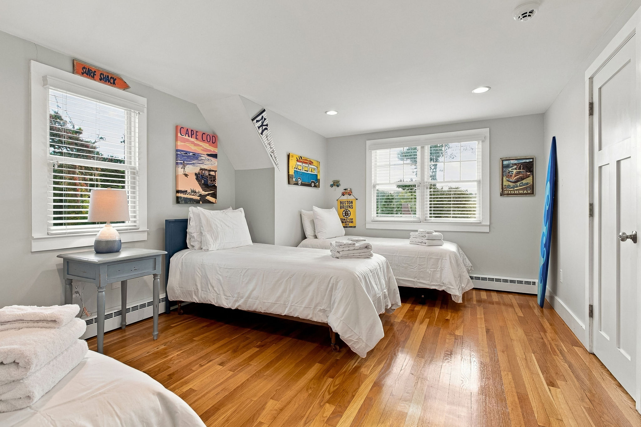 Bright coastal twin bedroom with hardwood floors and sunny windows