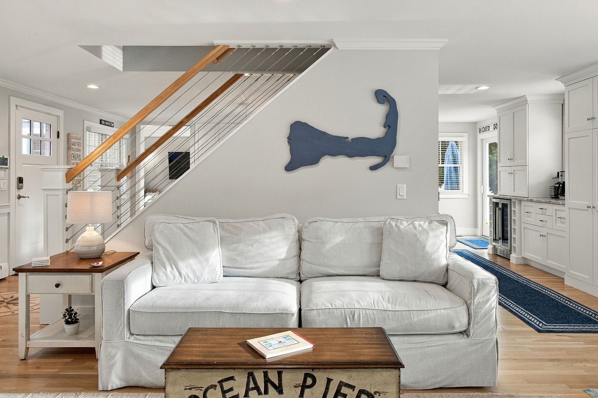 Bright coastal living room with comfy sofa and stylish modern staircase