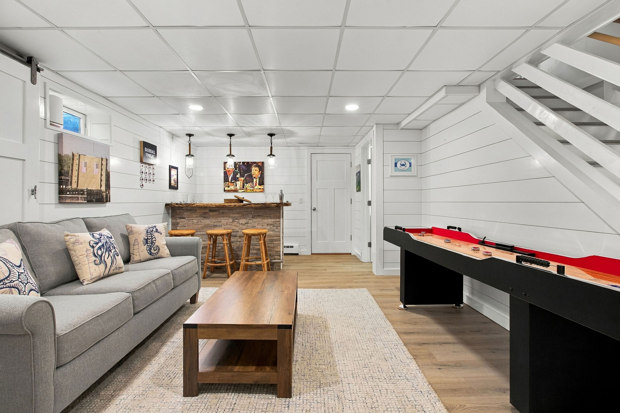 Cozy game room with shuffleboard, lounge seating, and bar area