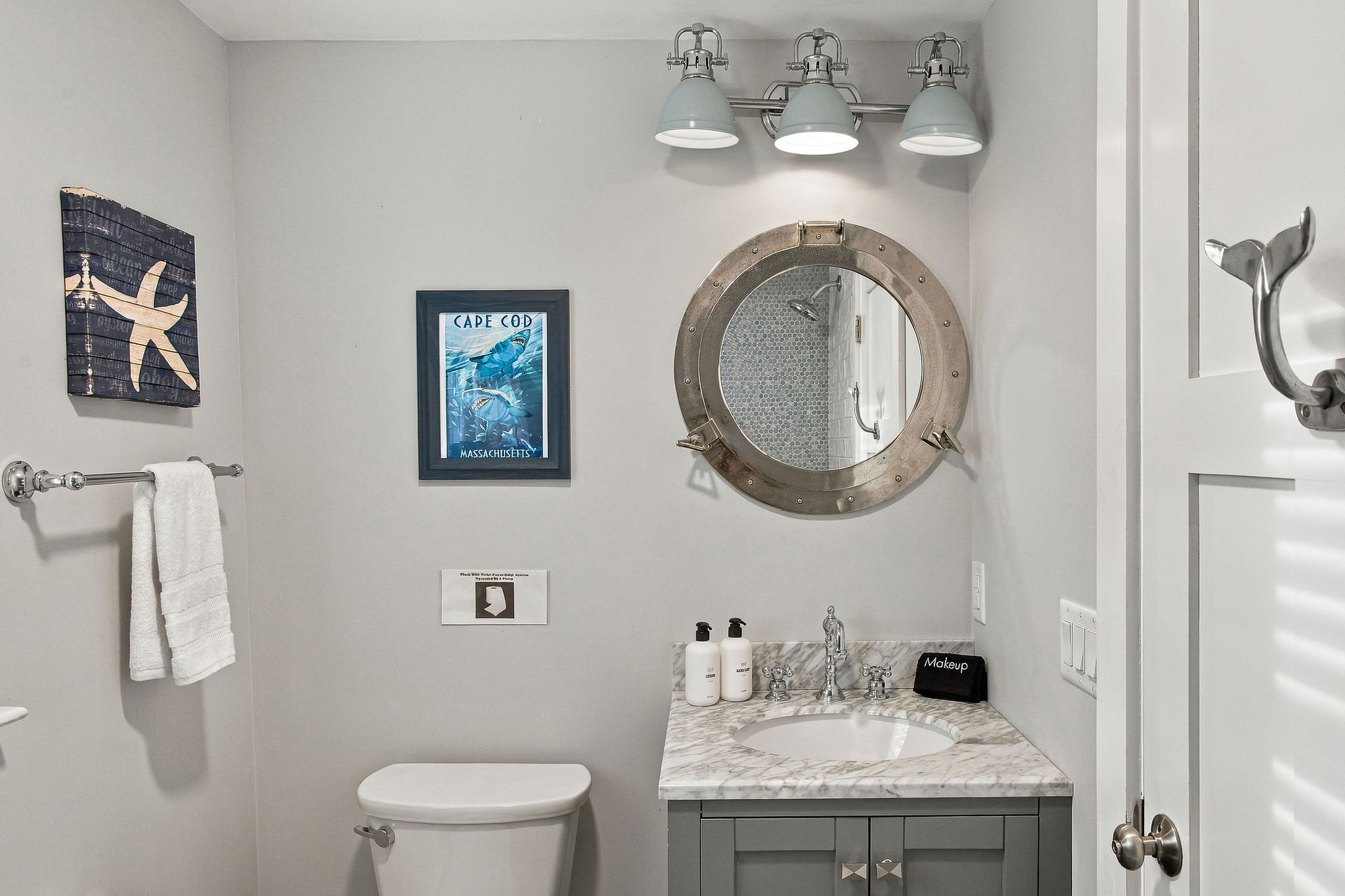 Coastal-inspired half bath with porthole mirror and elegant vanity