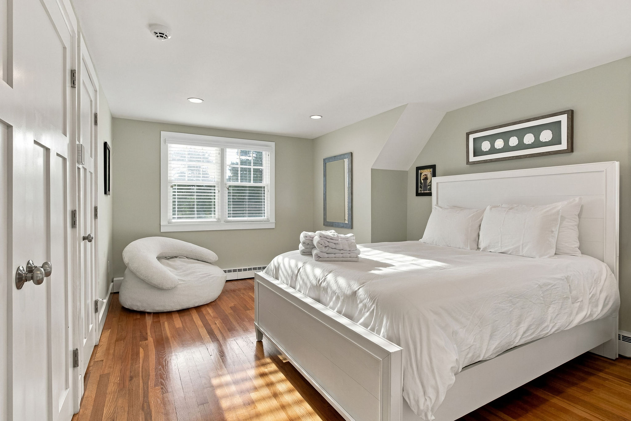 Bright, serene bedroom with hardwood floors and cozy natural light