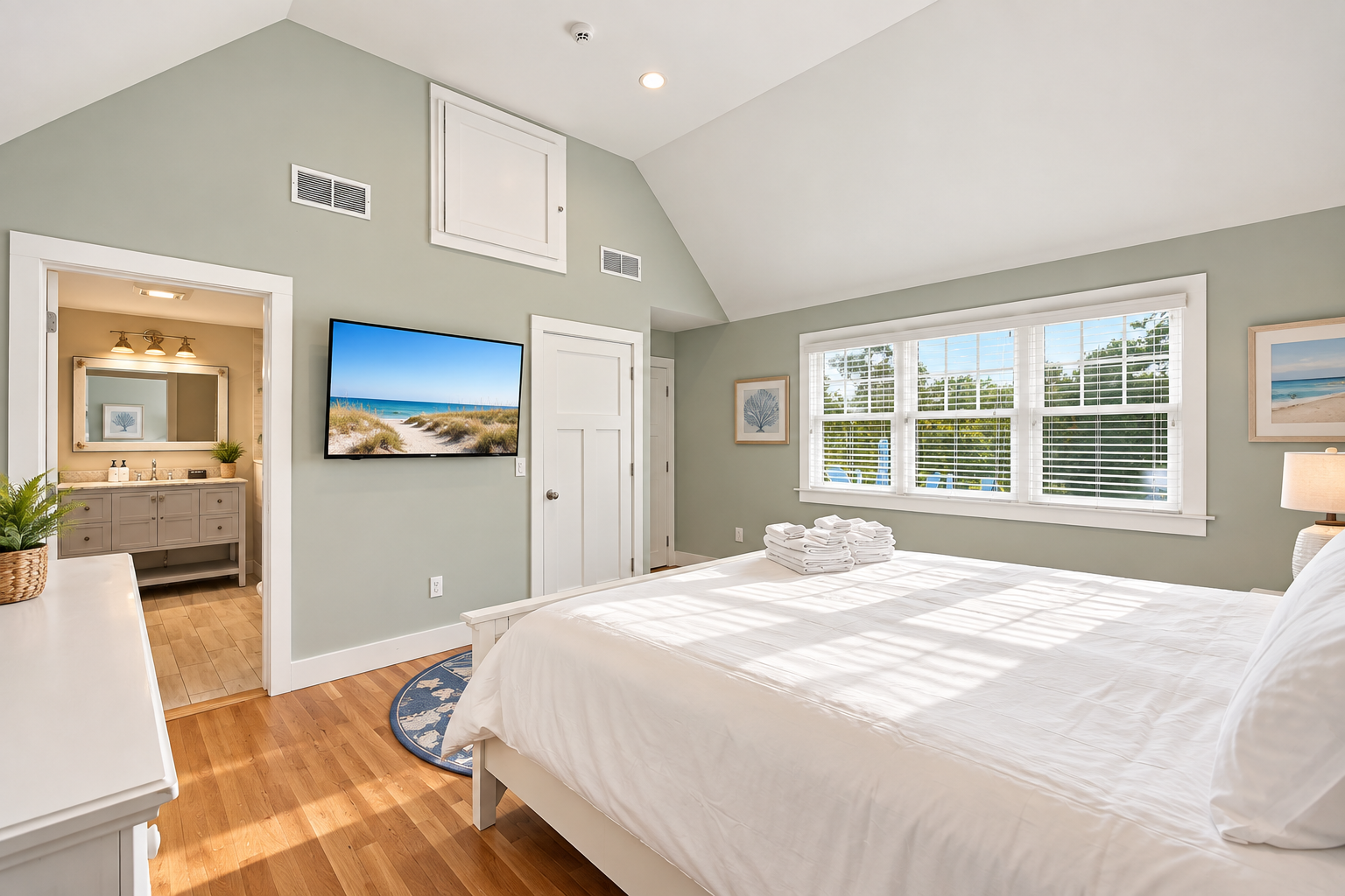 Sunny bedroom with vaulted ceilings, TV, and ensuite-style bath