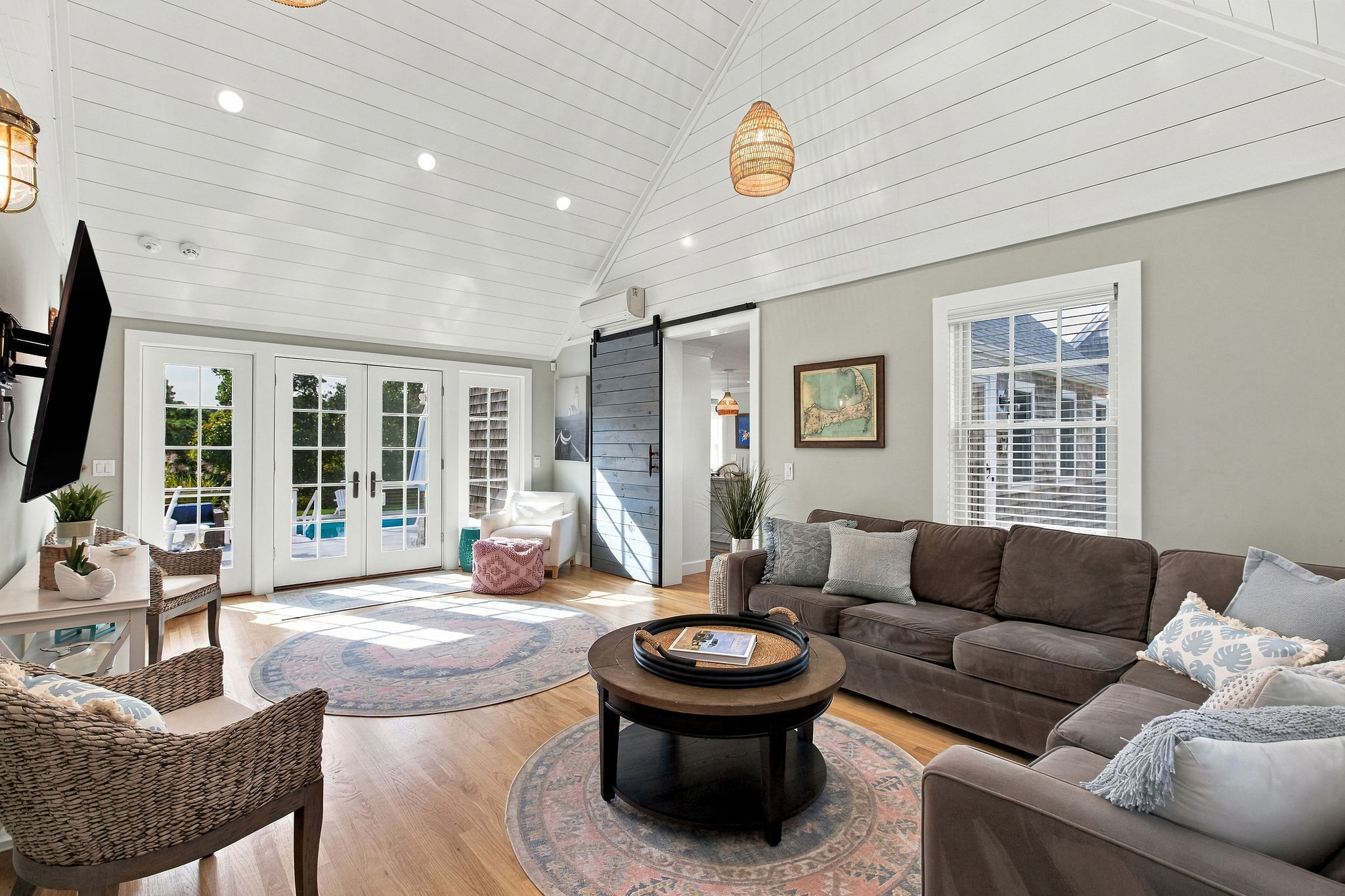 Bright coastal living room with vaulted ceilings and poolside access