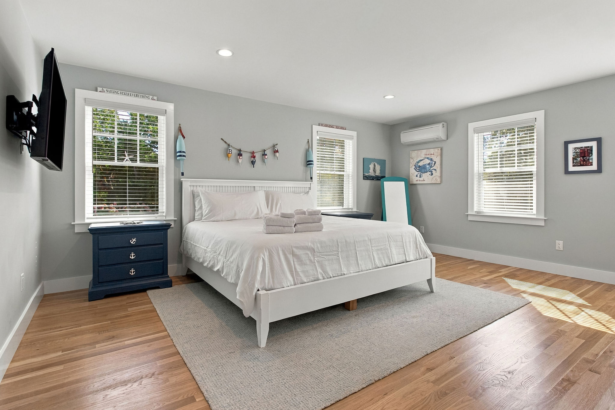 Bright coastal bedroom with king bed, TV, and abundant natural light