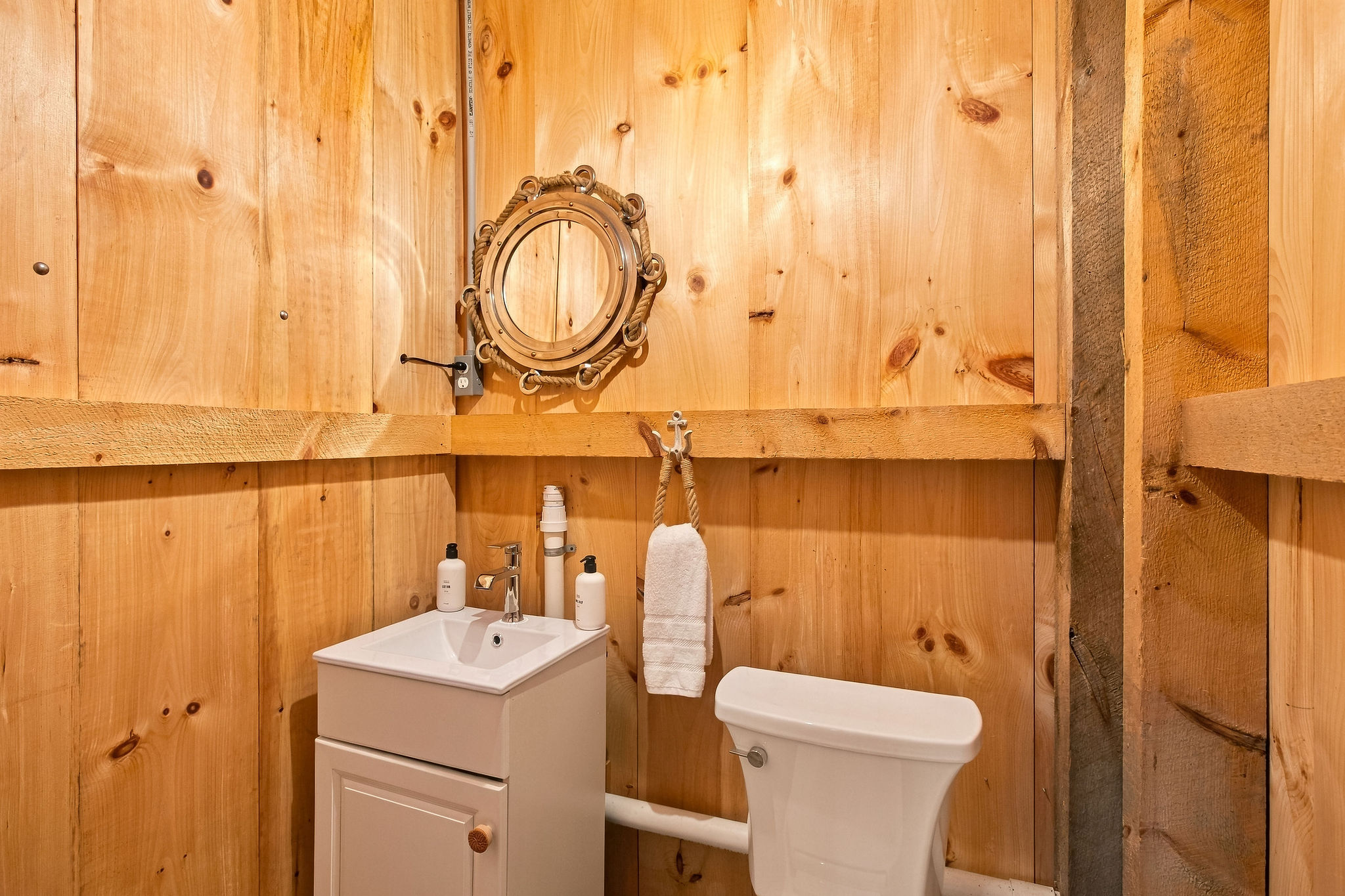 Cozy rustic half-bath with warm wood walls and charming cabin style