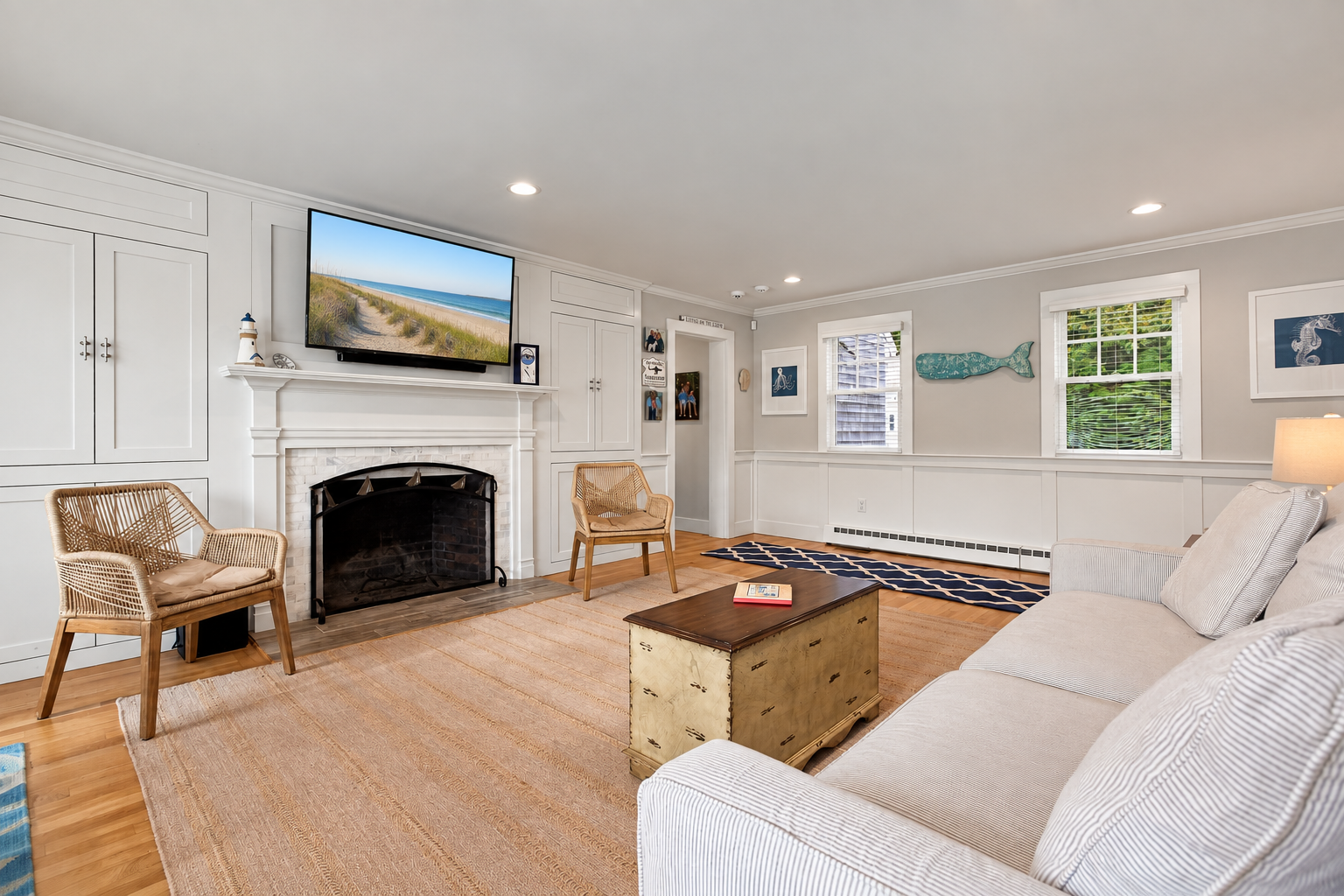 Bright coastal living room with fireplace, TV, and plenty of seating