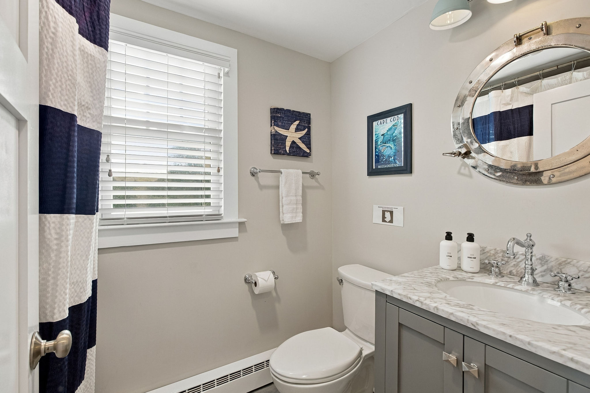 Bright coastal bathroom with marble vanity and charming nautical details