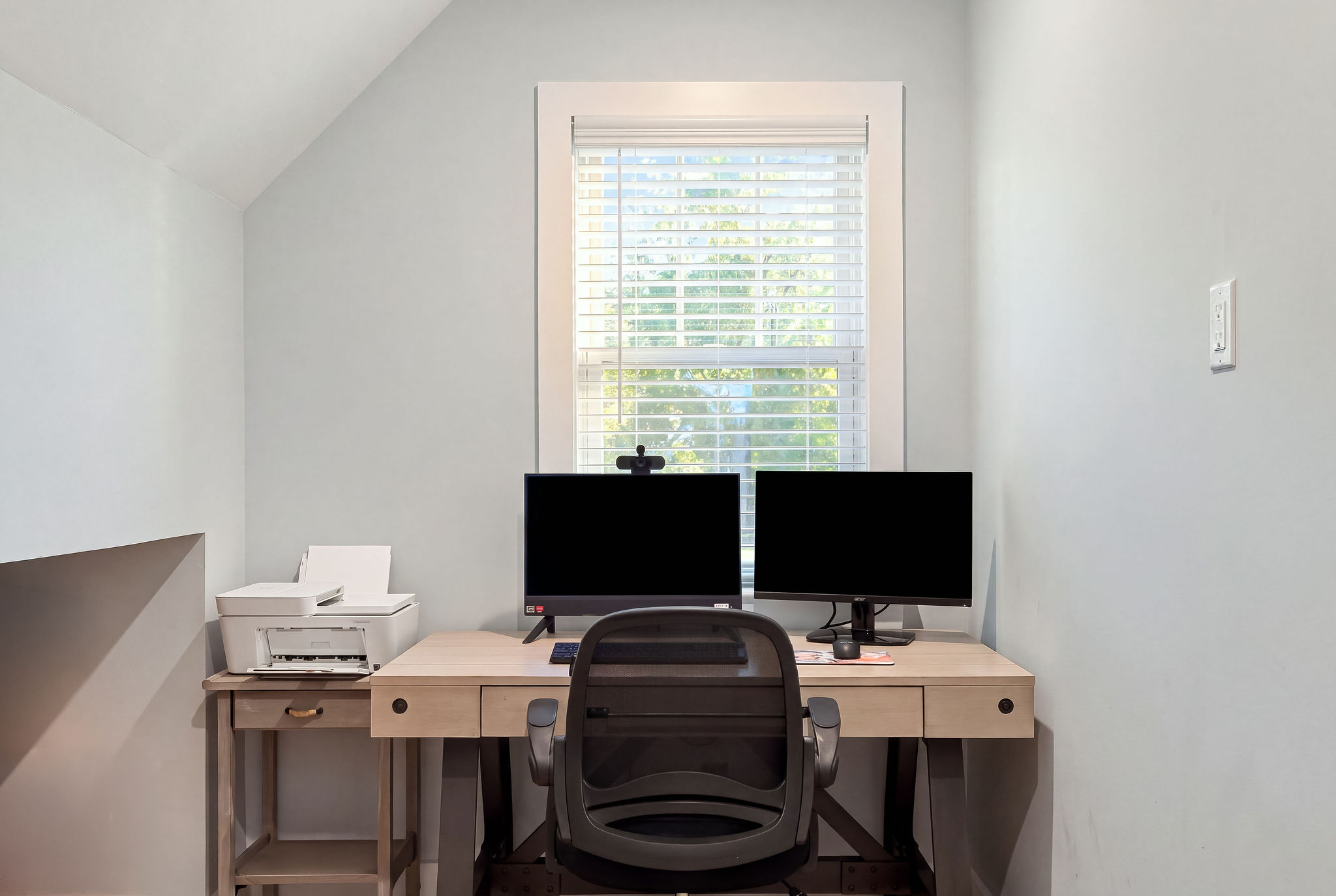Bright private workspace with dual monitors and natural light