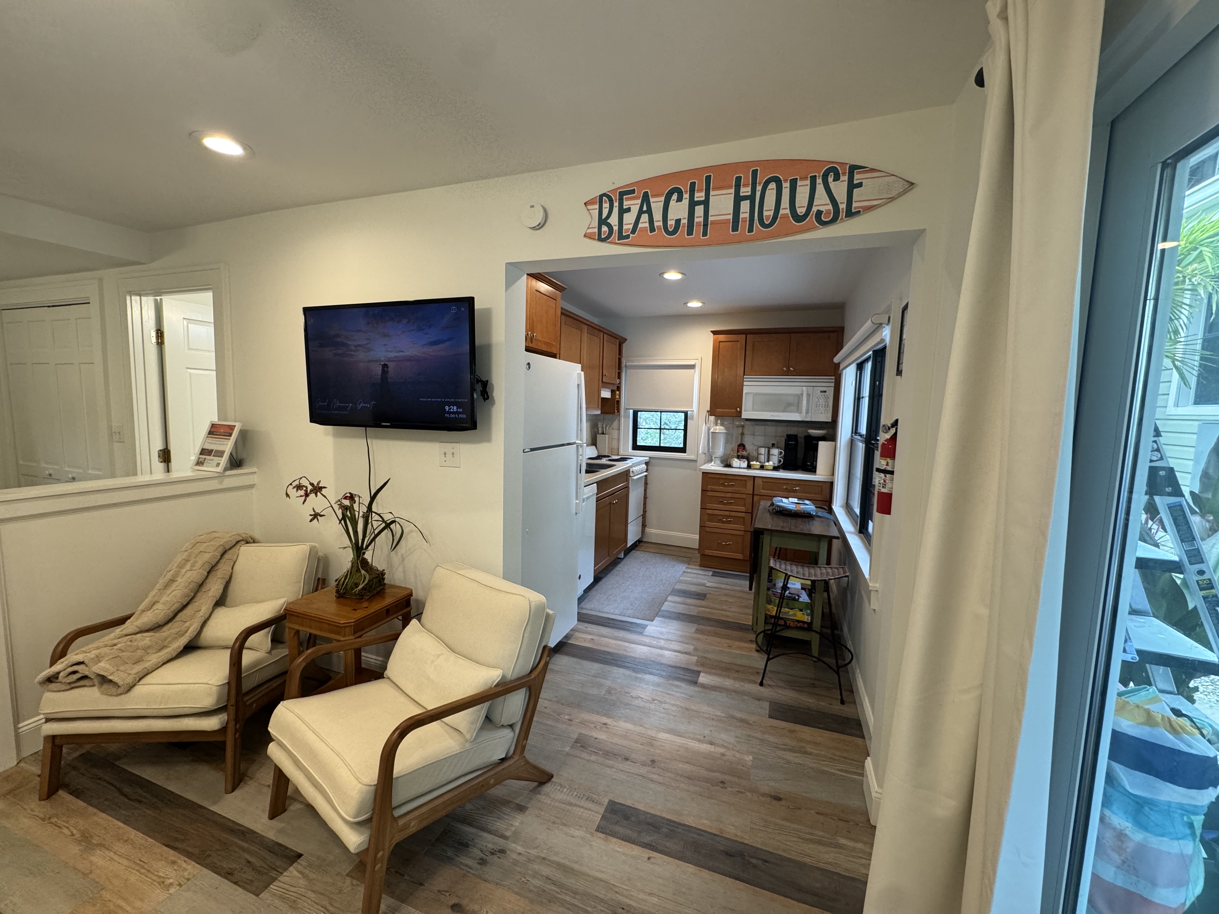 Cozy beach-house lounge with TV, natural light, and full kitchen