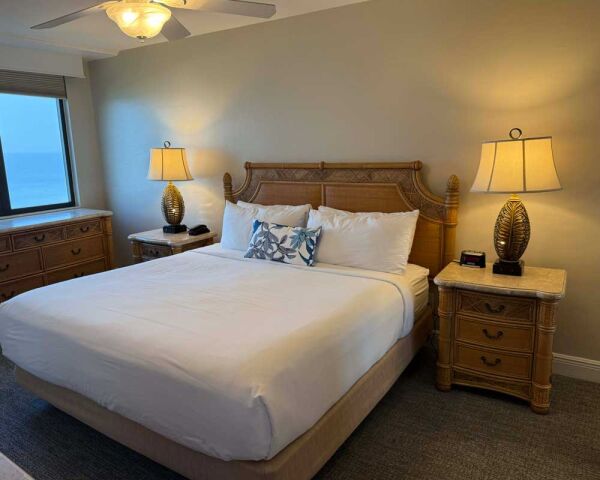 Cozy king bedroom with ocean view, elegant furnishings, and warm lighting