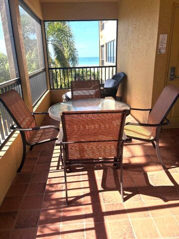 Screened balcony with outdoor dining and partial ocean views