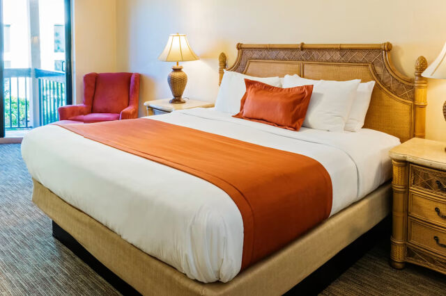 Bright resort-style king bedroom with balcony access and warm tropical accents