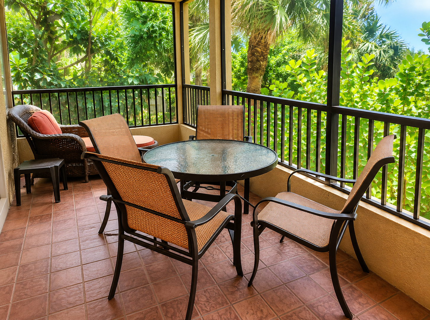 Screened tropical balcony with dining set and lush palm views