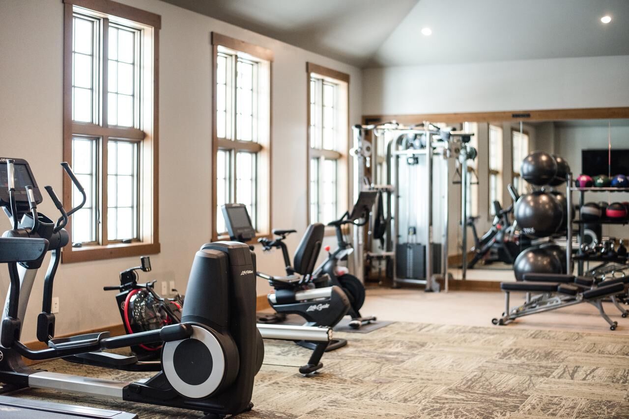 Bright on-site gym with cardio machines, weights, and natural light