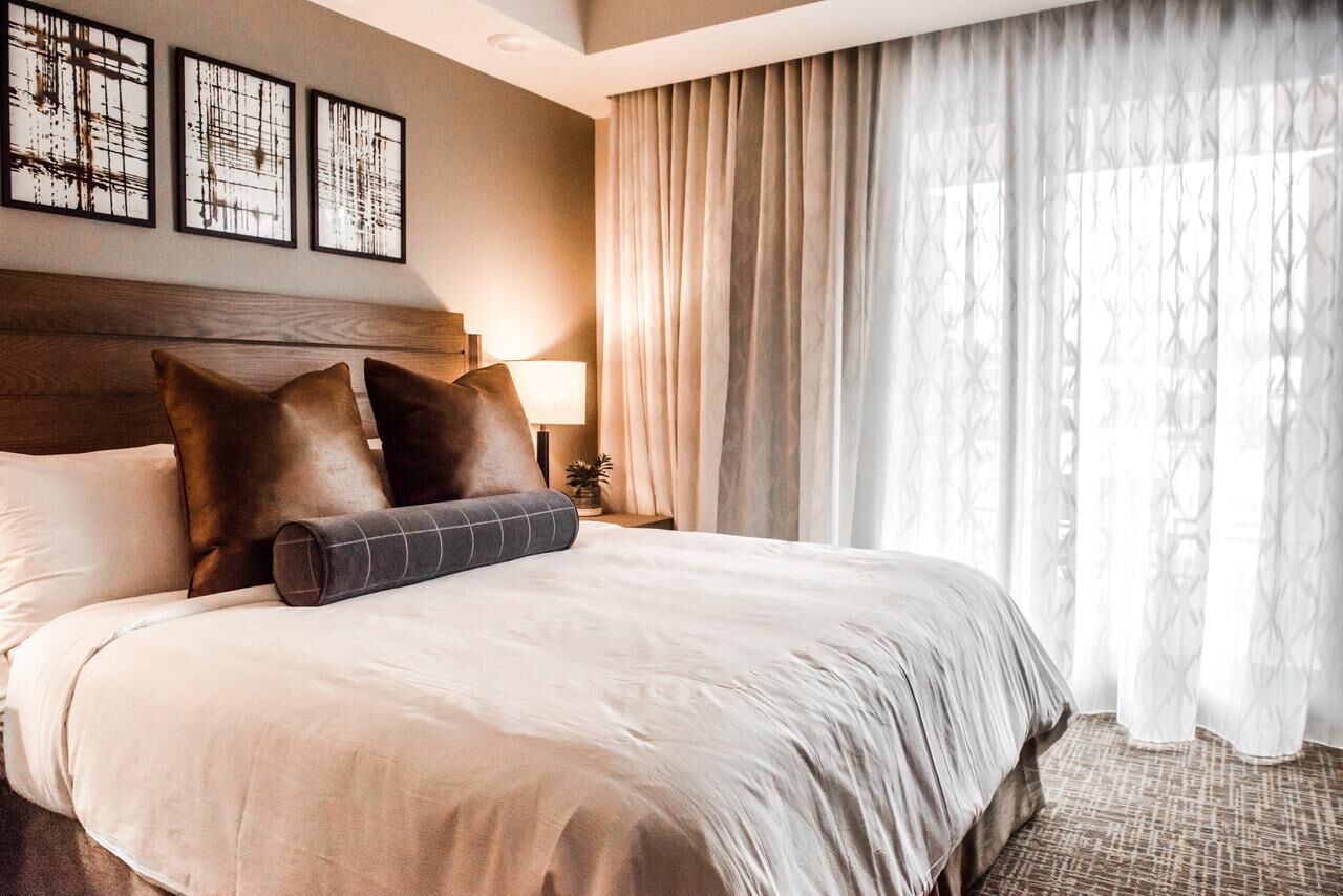 Bright, cozy bedroom with plush king bed and floor-to-ceiling window