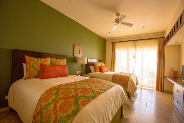 Bright double-queen room with colorful decor and sunny balcony doors
