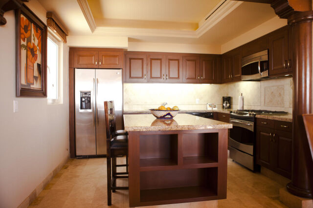 Elegant gourmet kitchen with island, stainless appliances, and rich wood finishes