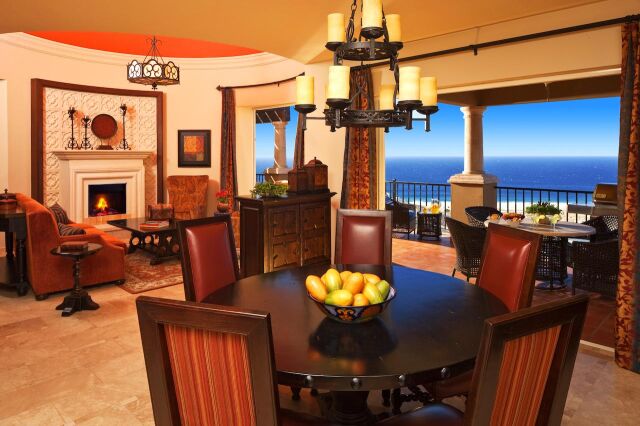 Elegant dining and living space with fireplace and stunning ocean-view balcony