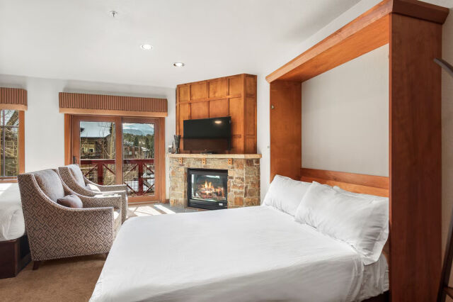 Cozy bedroom with fireplace, TV, and mountain-view balcony access