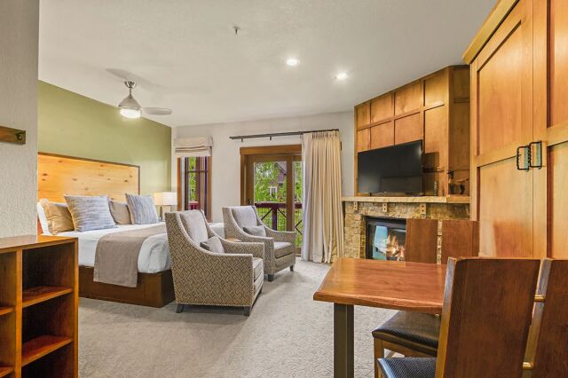 Cozy studio suite with fireplace, balcony views, and warm wood finishes