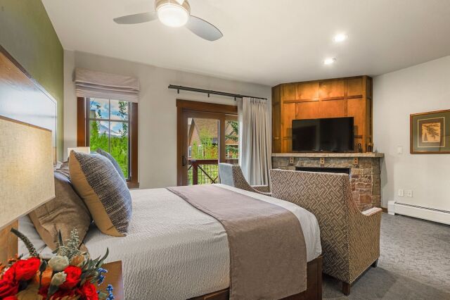 Cozy king suite with fireplace, TV, and private balcony views