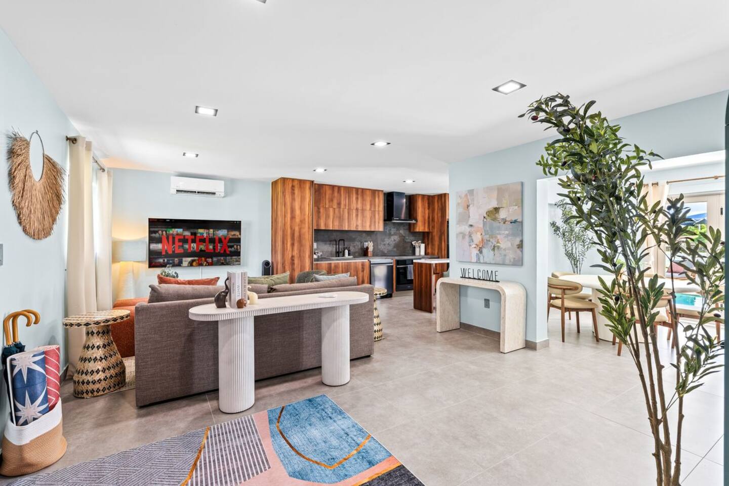 A comfortable living room with just the right touch of bright color. The open layout flows into the kitchen, creating a shared space that’s perfect for relaxing, dining, and spending time together.