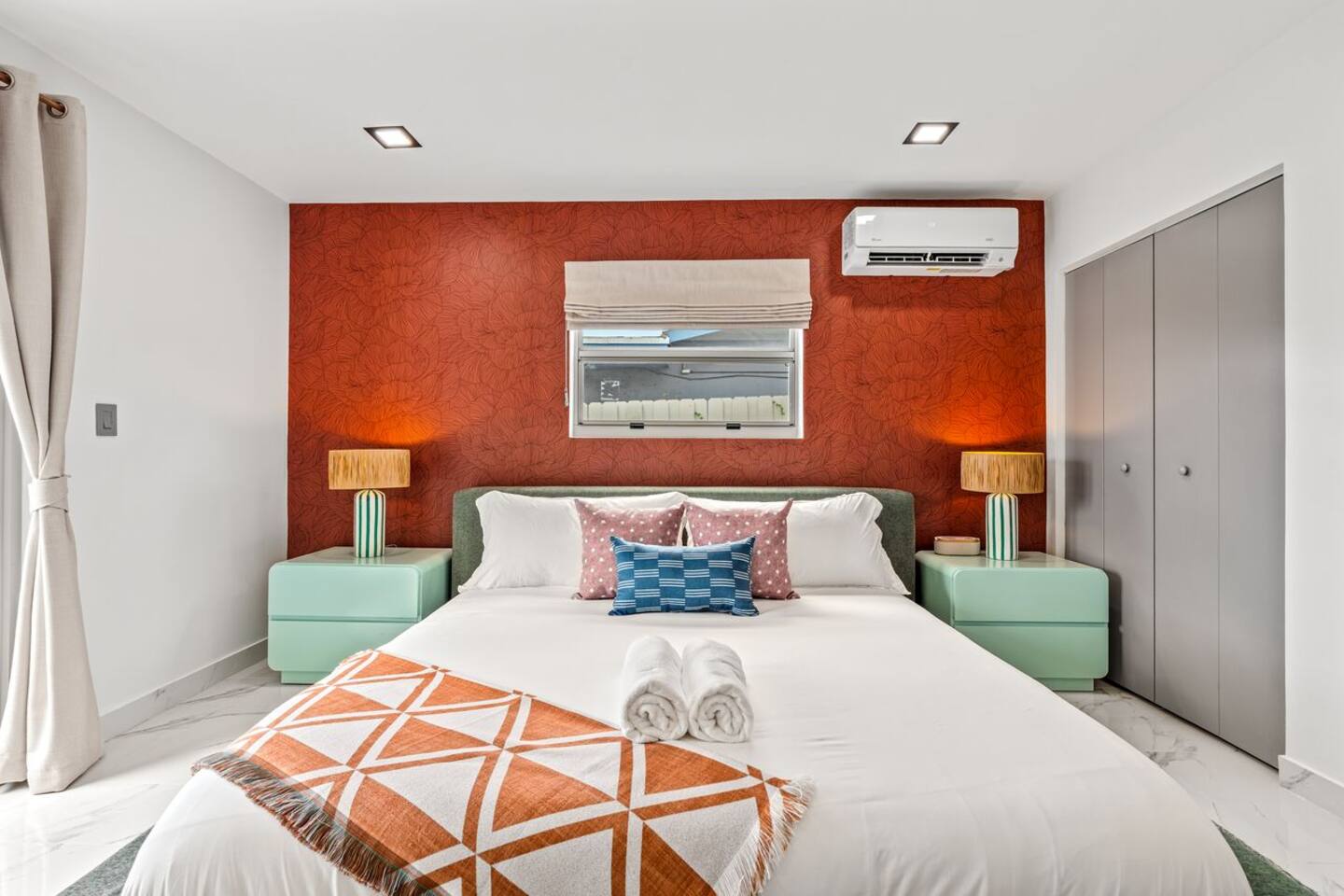 Relax in a comfortable king-size bed with a backyard view and access, private en-suite bathroom and TV, offering a peaceful space to unwind after a day at the beach.