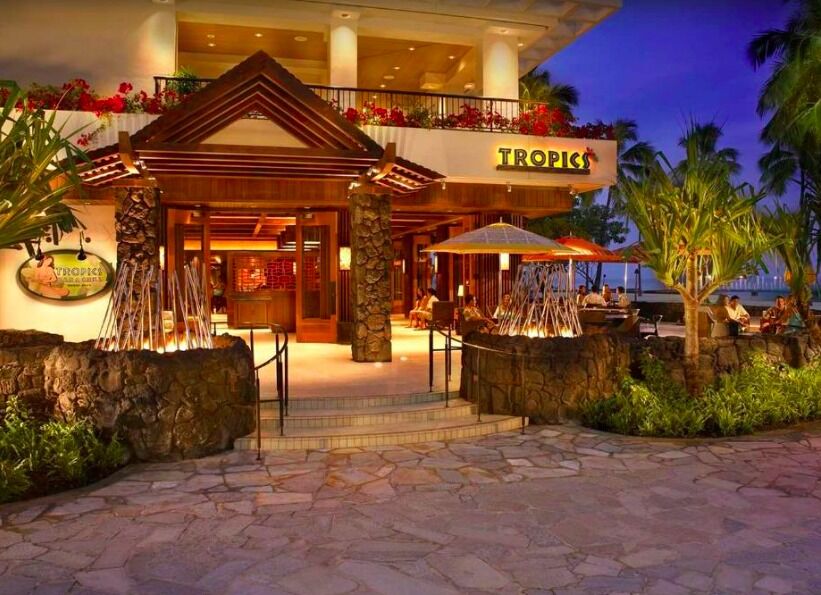 Elegant tropical resort entrance with open-air dining at dusk