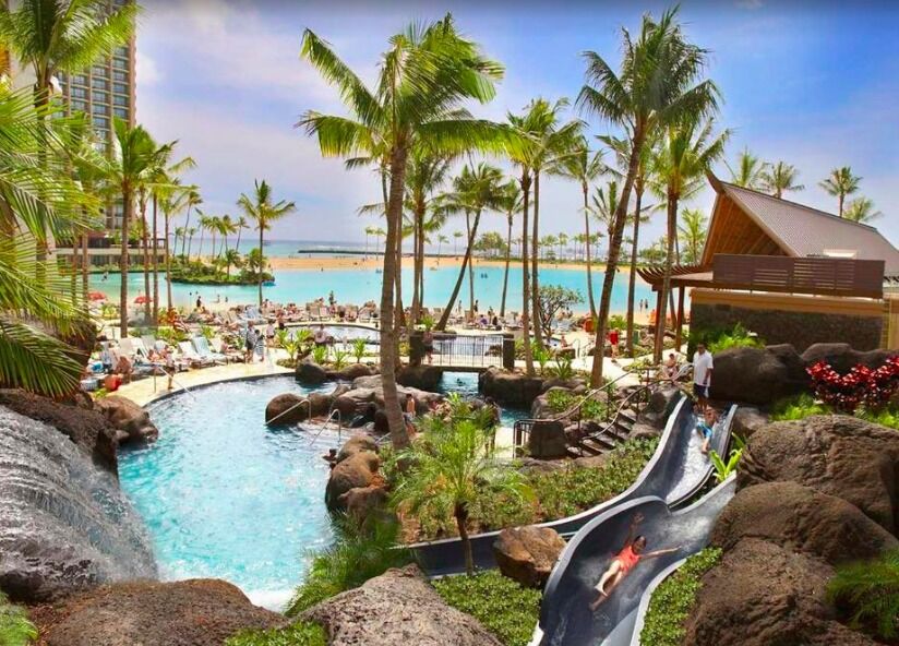 Tropical lagoon pool with waterslide, waterfalls, and beach views