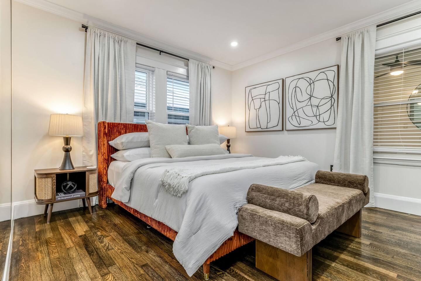 Spacious King bedroom with premium bedding, blackout curtains, and a cozy upholstered bench.