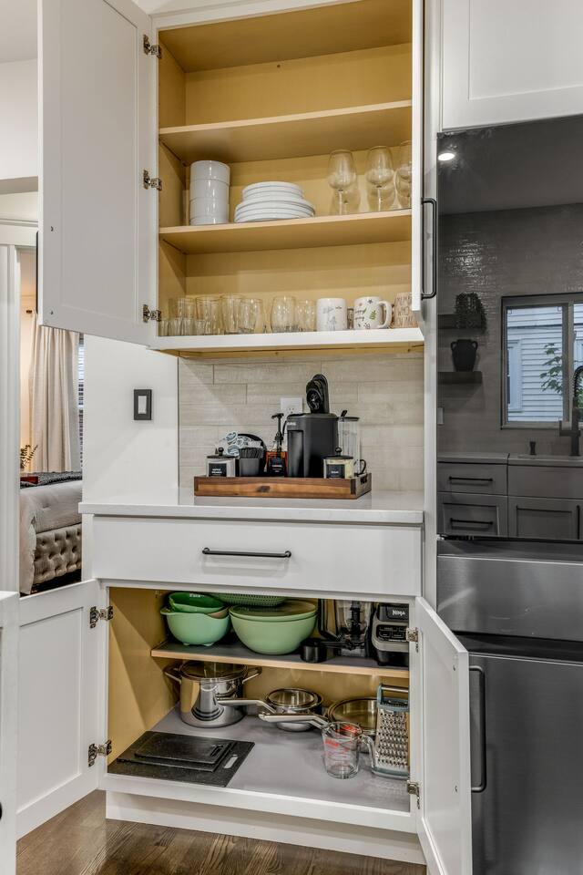 Fully stocked kitchen with cookware, dinnerware, glassware, and coffee essentials.