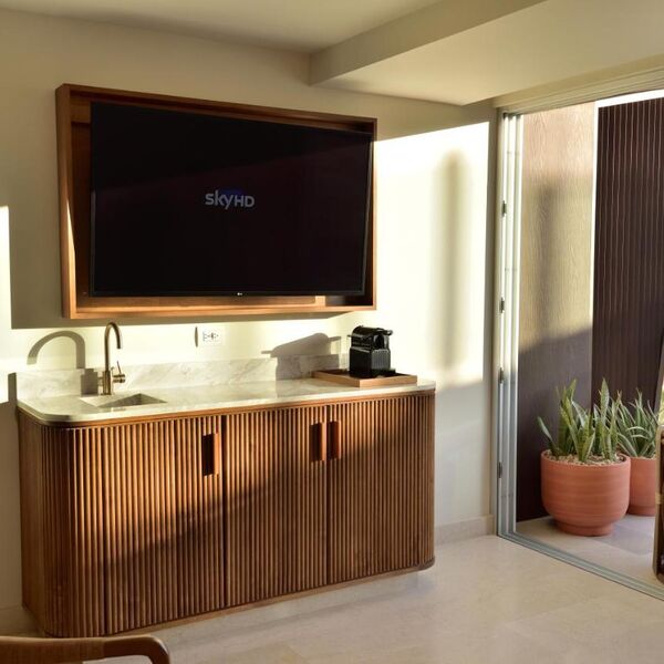 Modern wet bar with large TV, coffee station, and sunny patio access