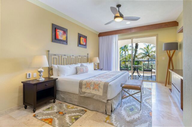 Bright king bedroom with private balcony and tropical palm views