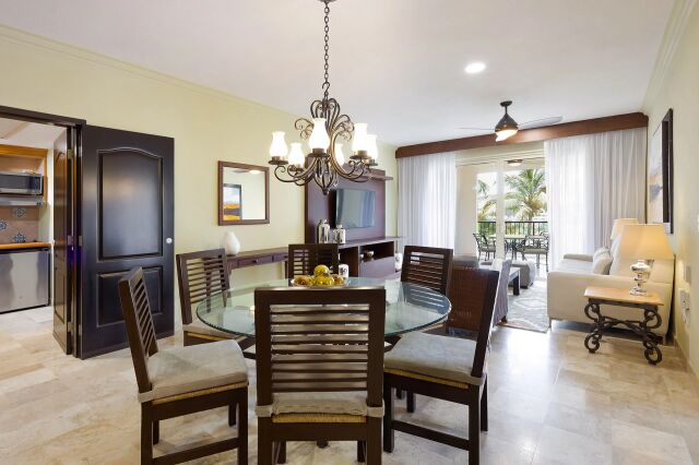 Bright dining-living space with balcony, tropical views, and seating for 6