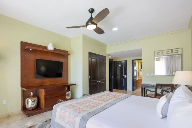 Bright, spacious bedroom with TV, ceiling fan, and elegant finishes