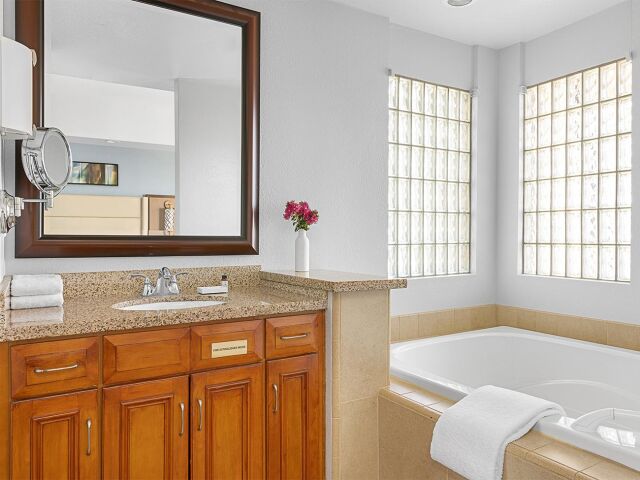 Bright spa-style bathroom with soaking tub and sunlit glass-block windows