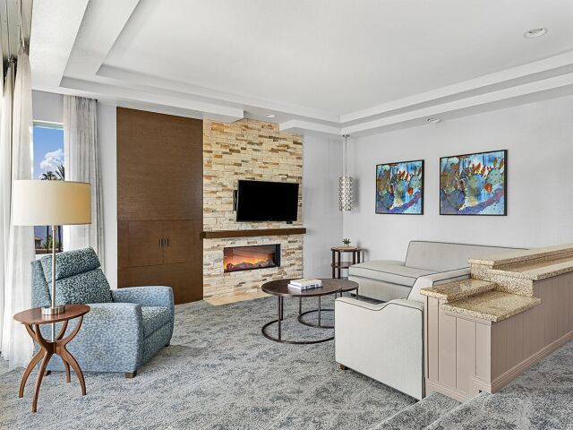 Bright upscale living room with stone fireplace, TV, and cozy seating