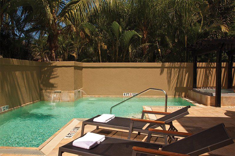 Tropical resort-style pool with loungers, cabana, and private ambiance