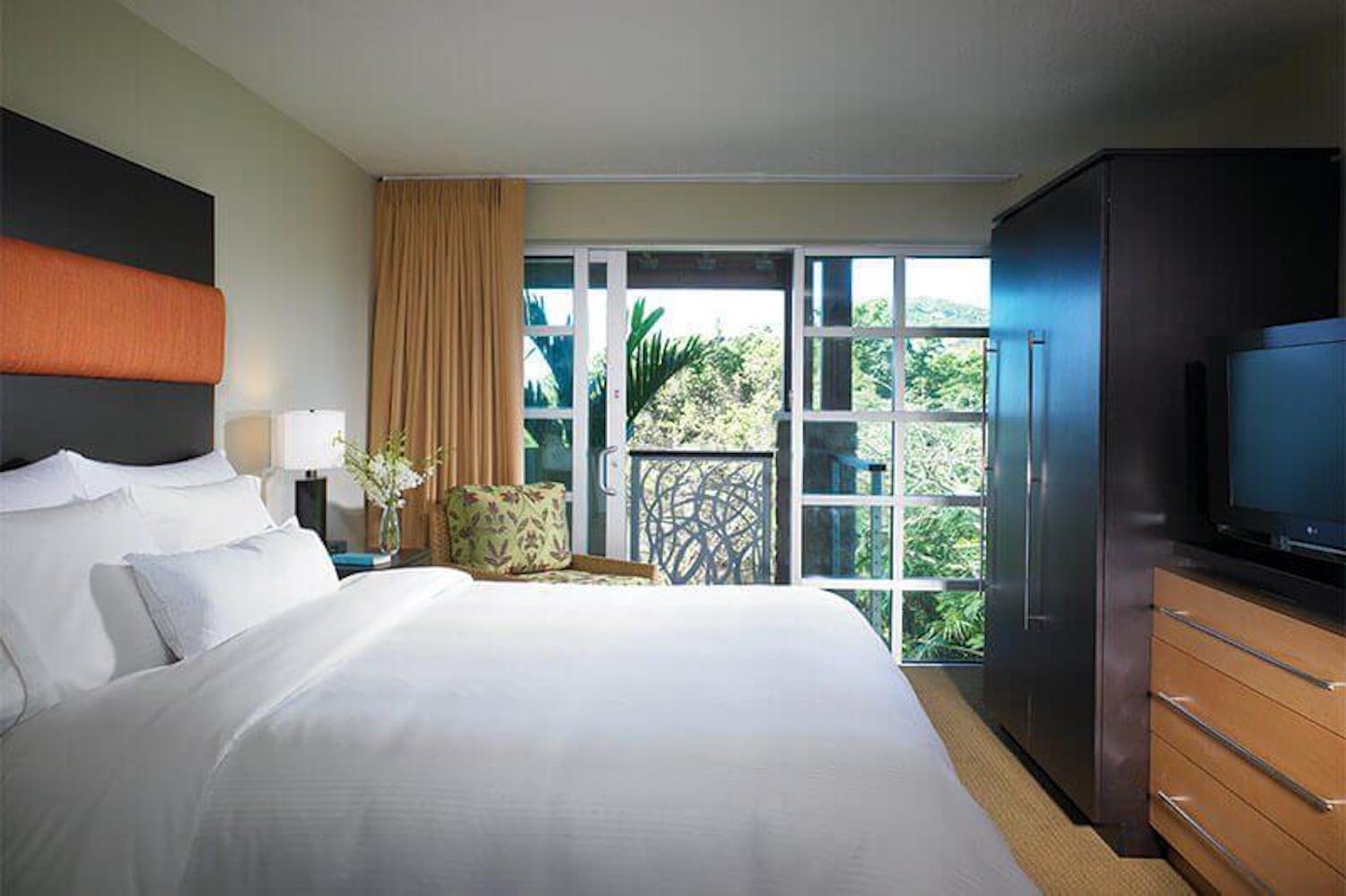 Bright modern bedroom with balcony access and lush garden views